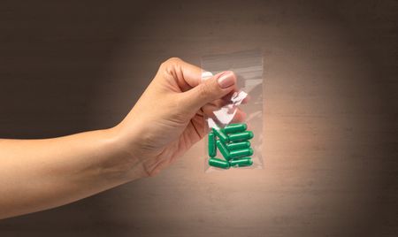 Naked, female hand giving drugs in plastic bag