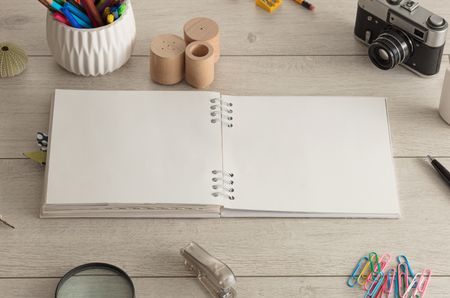 Empty notebook on wood floor with office tools nearby