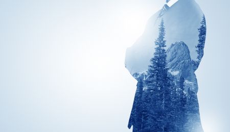 Young businessman standing and meditate with trees on the background 