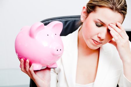 Worried woman with her savings in a piggy bank ? isolated