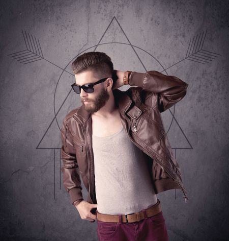 A young hipster male in modern clothes standing in front of an urban wall with modern sign illustration concept