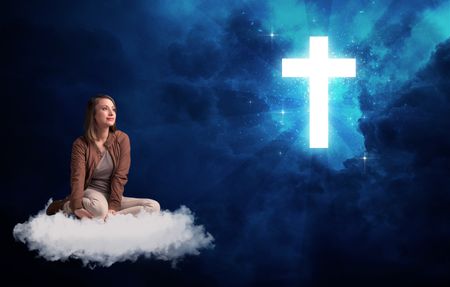 Caucasian woman sitting on a white fluffy cloud looking at a big, bright; blue; glowing cross