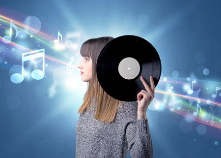 Young lady holding vinyl record on a blue background with musical notes behind her