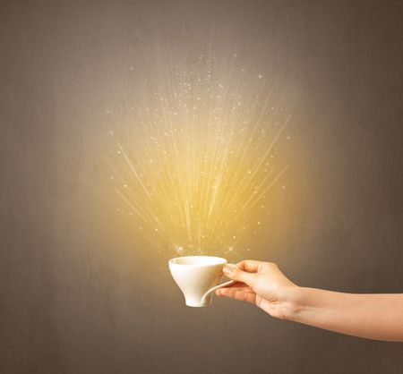 Young female hand holding coffee cup with a beam of light rising out of it