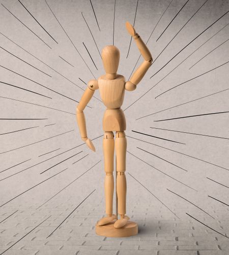 Wooden mannequin posed in front of a greyish background with black lines around him