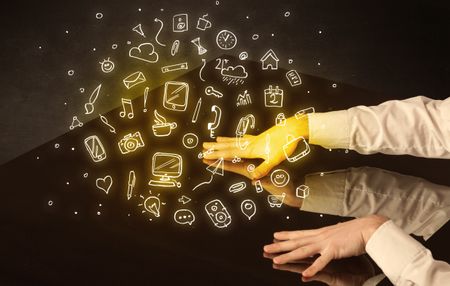 Male hands touching interactive table with yellow mixed media icons on it