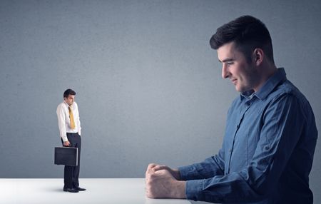 Young professional businessman being angry with an other miniature businessman 