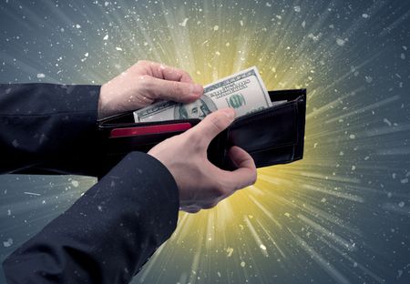 Businessman hand takes out dollar from wallet with fireworks background