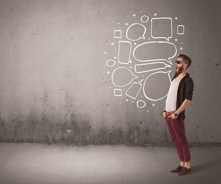 A comic hipster guy shouting in front of grey urban concrete wall with drawn empty text bubbles around his mouth concept