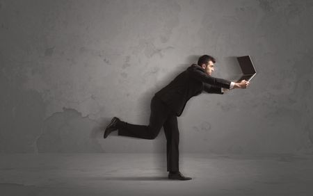 Running businessman in a rush with device in hand on background