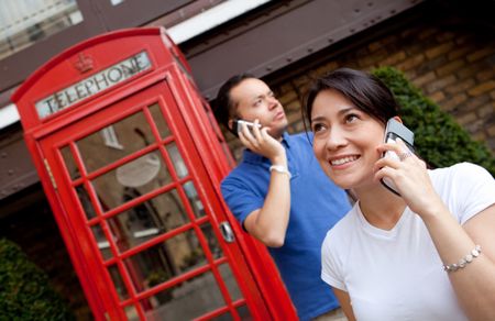 Couple talking on the phone outdoors in London streets