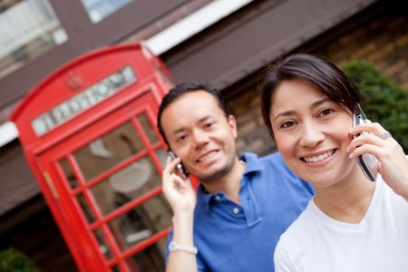 Couple talking on the phone outdoors in London streets