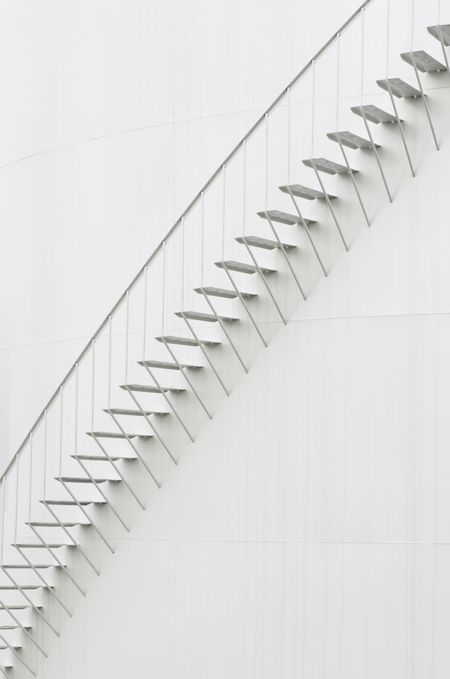 Industrial abstract: stairway curving along white exterior of petroleum refinery