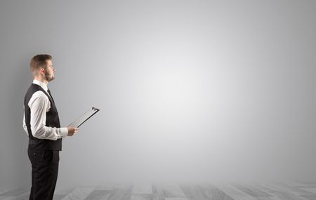 Elegant businessman standing and presenting something in an empty space with floor
