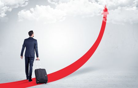 Young businessman with back leaving on the red arrow carpet to the skies with luggage on his hand