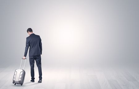 Young businessman in a white boundless space walking with back and luggage on his hand