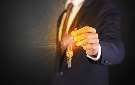Formal man hand over shiny keys with dark background
