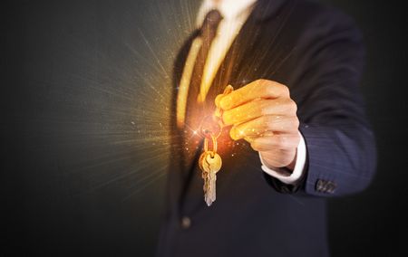 Formal man hand over shiny keys with dark background