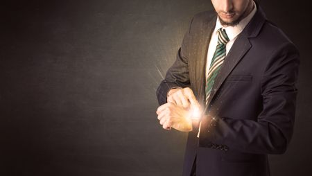 Businessman wearing smartwatch with shiny rays on it.