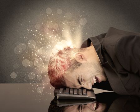 young-depressed-business-person-laying-head-787855702 A young depressed business person laying his head on computer keyboard with thoughts exploding from his head illustrated by light beams concept