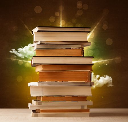 Magical books with ray of lights and colorful clouds on vintage background