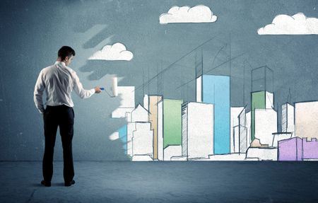 An elegant businessman standing with a paint roller transforming a blue wall into urban city landscape drawing sketch including skyscrapers and clouds concept