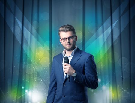 Businessman speaking into microphone with blue curtain behind him