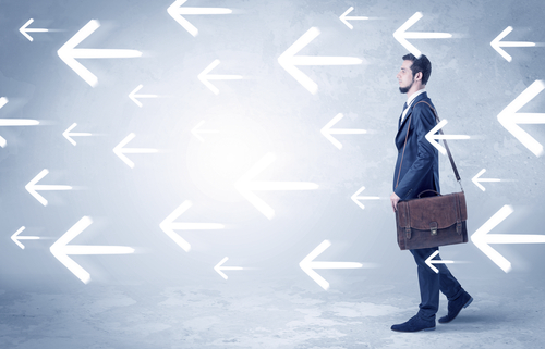 Businessman walking with arrows on the background and briefcase on his hand
