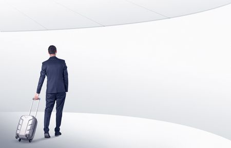 Businessman with back walking in a white waiting room with empty walls around
