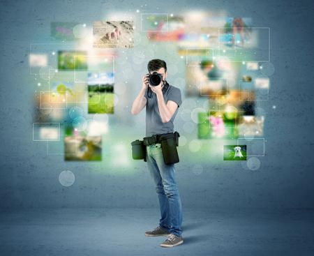 A young amateur photographer with professional camera equipment taking picture in front of blue wall full of faded pictures and glowing lights concept