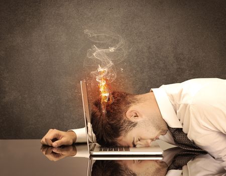 A frustrated businessman resting his head on a keyboard and shouting with his hair on smoke, catching fire