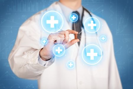 A male doctor in coat in front of a blue wall holding a pill between his fingers with lines and white crosses in circles