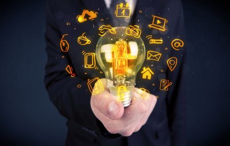 An office salesman promoting his bright ideas concept with illustration of online media and device logos around electric glass light bulb.