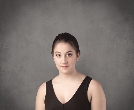 pretty-young-teenage-girl-standing-front-787996981 A pretty young teenage girl standing in front of a grey clear empty urban wall background concept while making funny faces.