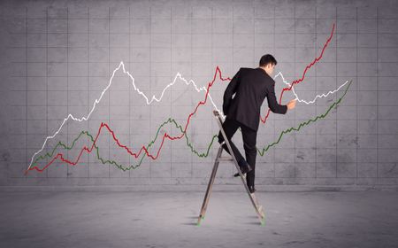 A guy in modern suit standing on a small ladder and drawing a chart on grey wall background with exponential progressing curves, lines