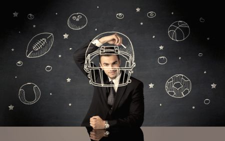 A happy college graduate dreaming about becoming a successful sports person while drawing helmet and ball in space concept