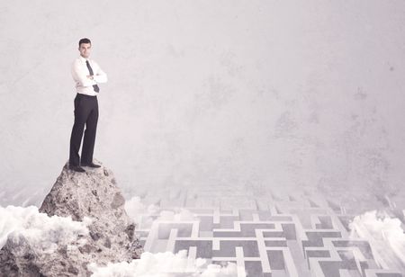 Maze is no challenge for successful businessman standing on top of a cliff as he is the best at solving problems concept