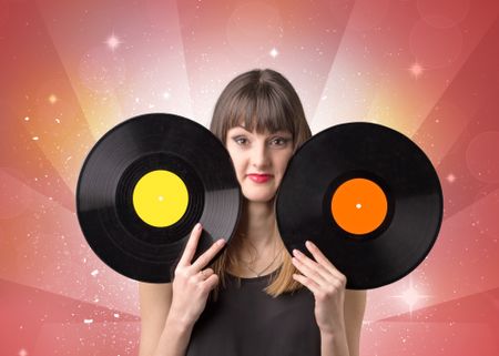 Young lady holding vinyl record on a red background with lights shining behind her