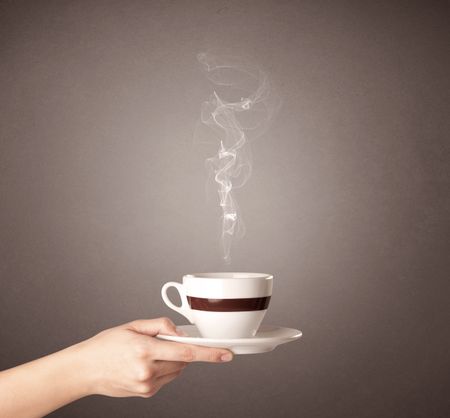 Young female hand holding steaming coffee cup 