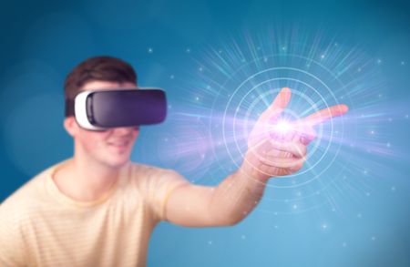 Young impressed man wearing virtual reality goggles with blue circles around his finger