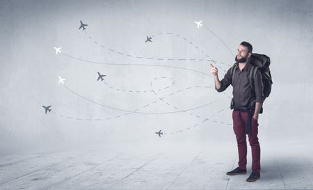 Handsome young man standing with a backpack on his back and little planes in the background