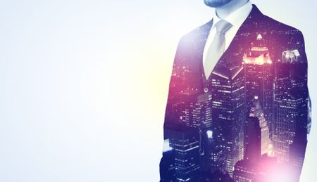 Young businessman thinking and standing with night skyscraper background