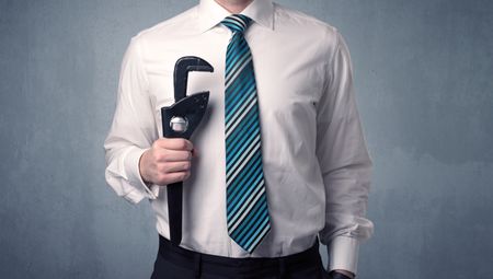 Young, handsome, cute businessman holding tool with grey background