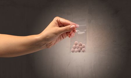 Naked, female hand giving drugs in plastic bag