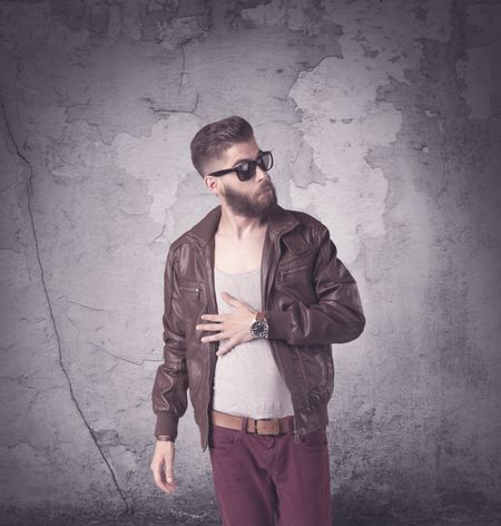 Funny vintage guy with long beard and stylish hair standing in front of urban concrete wall concept