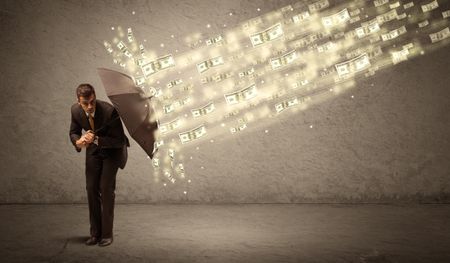 Business man holding umbrella against dollar rain concept on grungy background