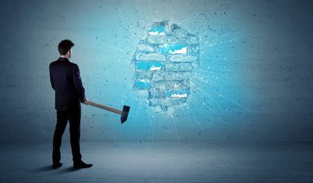 Business man hitting grungy brick wall with huge hammer