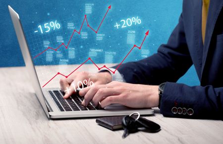 An elegant businessman working on graph statistics calculation using a laptop with clear blue background concept