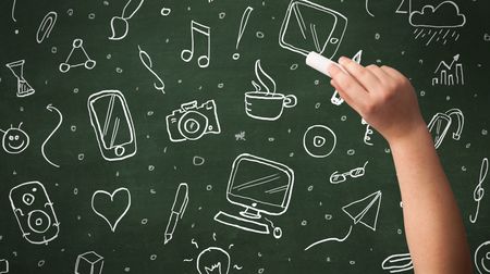 A person drawing media and communication icons on school blackboard with chalk
