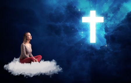 Caucasian woman sitting on a white fluffy cloud looking at a big, bright; blue; glowing cross